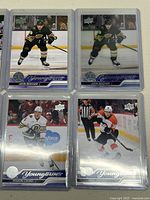 Four hockey cards including John Beecher in both base and acetate versions, Mason Lohrei, and Eric Robinson Young Guns cards in sleeves.