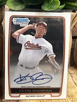 Front of 2012 Kevin Gausman Bowman Chrome rookie baseball card showing image of player in Orioles uniform with autograph signed in blue ink across lower part of card.
