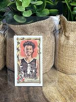 Front view of Victor Wembanyama basketball rookie mini card in protective sleeve with illustrated portrait and red background.