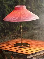 Used pink and gold outdoor solar lamp displayed on a wooden surface.