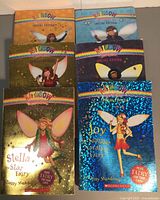 Photo showing six colorful Rainbow Magic Special Edition books stacked, each featuring a different fairy character on the cover with foil details.