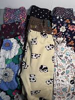 Nine pairs of girls leggings stacked and folded showing variety of prints and brands, including floral, panda, polka dots, whimsical and woodland themes.