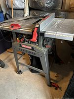 Front view of Craftsman table saw showing overall condition, metal table surface, red adjustment knobs, and stand with wheels.