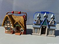 Photo shows two Disney mini houses: Snow White's house with yellow thatched roof and Elsa's house with blue dormer windows