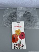Two unopened packs of silver blossom crowns and a WebVase flower arranger card lying on a flat surface