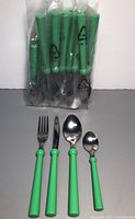 Cutlery pieces with green handles including forks, knives, tablespoons, and teaspoons packed in clear plastic bags.