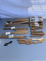 Full view of various wooden kitchen utensils laid out, showing different shapes and sizes including spreaders, spatulas, and tongs.