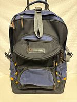 Front view of multifunction backpack-style suitcase with multiple compartments and black, navy blue and orange fabric