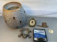 Top view of ceramic plug-in wax melter, small framed silhouette art piece, curved metal magnifier, carved wooden goose figurine and boxed Hoselton sailboat sculpture