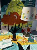 Duvet cover and pillowcases arranged behind and underneath a lit table lamp with matching animal print shade against the background of the duvet cover design.