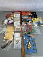 Photo showing a variety of small tools and gadgets including brushes, screwdriver, key tag labels, needle threader, and the pocket stove packaging.