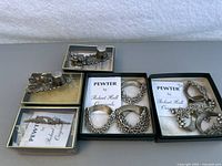 Overview of all items in lot: two sets of pewter napkin rings, two thimble holders, and one brooch, all by Robert Hall.