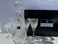 Full view of four crystal wine glasses and a crystal decanter with stopper, all labeled with Royal Doulton tags, arranged in front of the original Royal Doulton gift box.