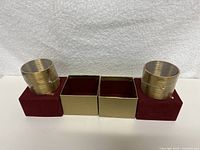 Two gold-colored Slinkys displayed on burgundy velvet cushions inside open gold-colored boxes.