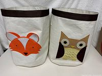 Front view of two toy bins side by side, one with a fox face and one with an owl face.