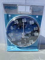 Hydrotools thermometer in sealed packaging, beach-themed background, Fahrenheit and Celsius scales visible
