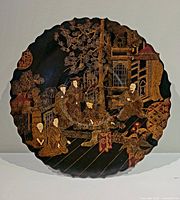 Front view of the antique Asian wood plate showing detailed carved scene with figures and architecture.