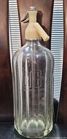 Front view of antique N.B.W.L. Montreal seltzer bottle with etched markings and siphon top.