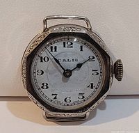 Front view of the antique Calis wristwatch showing white dial with black numerals, ornate octagonal case and winding crown
