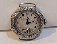 Front view of antique Hudson wristwatch with octagonal engraved case showing dial, numerals, and hands.
