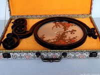 Chinese embroidery artwork with bird and blossom design in a round wooden frame with carved handle, inside open fabric-lined decorative display case.