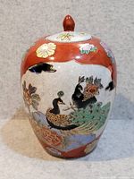 Front view of the Chinese lidded ginger jar showing the red background, floral patterns, and two peacocks with gold accents.