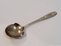 Large silver spoon with rounded bowl, showing engraving and signs of age and use.