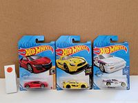 Three Hot Wheels cars in original sealed packaging: red Acura NSX, yellow sports car, white Honda with number 20 decals