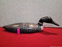 Side view of wooden duck decoy showing detailed paint and size reference with a lighter