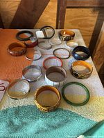 Overview of 15 assorted bangle bracelets including various colors and designs such as floral patterns, stripes, and solid colors.
