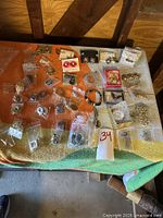 Overview of a large quantity of vintage jewelry spread out on cloth showing various earrings, brooches, and bracelets in plastic bags and boxes.