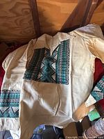 Beige men's ethnic shirt with teal and black embroidery on front and sleeves.