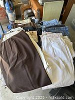 Photo showing folded pants and skirts in brown, white, and beige tones.