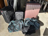 Photo showing full set of six luggage pieces including the large rose gold hardside suitcase, two black soft-side suitcases, two matching polka dot duffle bags, and smaller black bag.