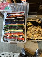 Two plastic bins filled with folded men's short-sleeve shirts showing a range of colors and patterns, stacked neatly.