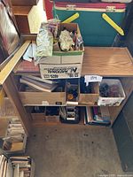 Overview of cardboard boxes and containers filled with assorted office supplies on wooden shelving unit