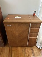 Full image of the Janome sewing machine cabinet showing the wooden finish and front design.