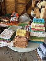 Photo showing stacked new bath towels, hand towels, and washcloths on a round table in various colors and textures.