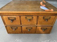 Front view of stacked card catalog drawers showing six total drawers with brass label frames and pulls.