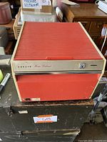 Front view of red Kokuyo Home Cabinet with roll-top door and lock.