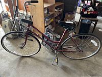 Side view of maroon Schwinn women’s bicycle showing full bike with leather saddle, black grips, thin tires, and frame details.