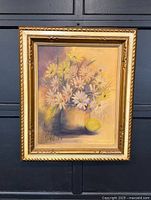 Front view of framed floral oil painting showing white and yellow daisies in vase with lemon beside it, signed and dated '73