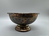 Side view of silver plated trophy inscribed with "The Corby Trophy Winner 1965." Visible tarnish and wear on the surface.