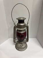 Front view of the metal lantern with red globe and wire handle, showing embossed Dietz branding on top section.