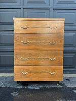 Front view of full dresser showing four drawers, brass handles, tapered legs