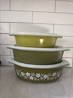 Stacked three Pyrex casserole dishes in Spring Blossom Green with white floral pattern on the bottom dish and solid green on the others.