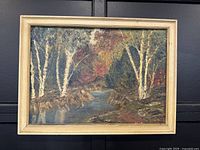 Framed oil painting showing a rocky river scene with birch trees and autumn foliage, signed.