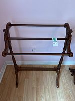Front view of the wooden blanket rack showing three horizontal rods and curved sides.