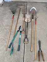 All 9 garden tools laid out on concrete floor showing shape, size, and condition for assessment.