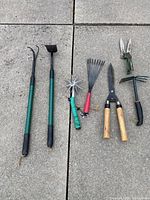 All seven garden tools laid out on pavement in two images showing full set with varied tools for cultivation, cutting, and raking.
